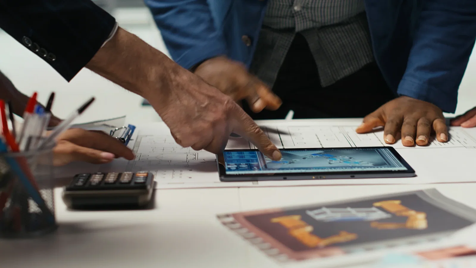 An engineering team using a tablet to analyze large-scale robotic fleet management and industrial layouts.