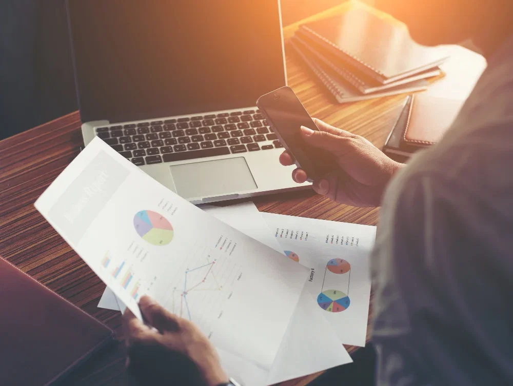 B2B industrial project manager performing a technical review of business reports and data charts.
